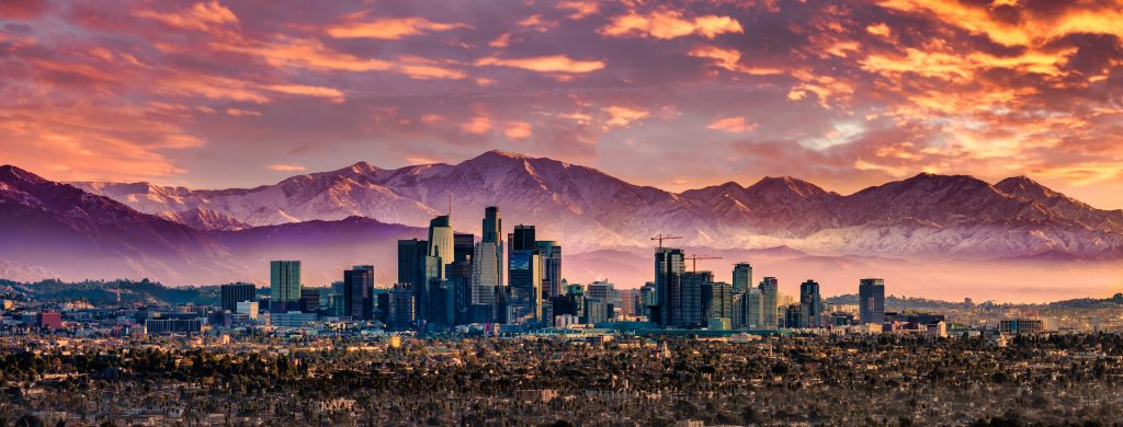A view of the Los Angeles skyline with snowcapped mountains in the background
