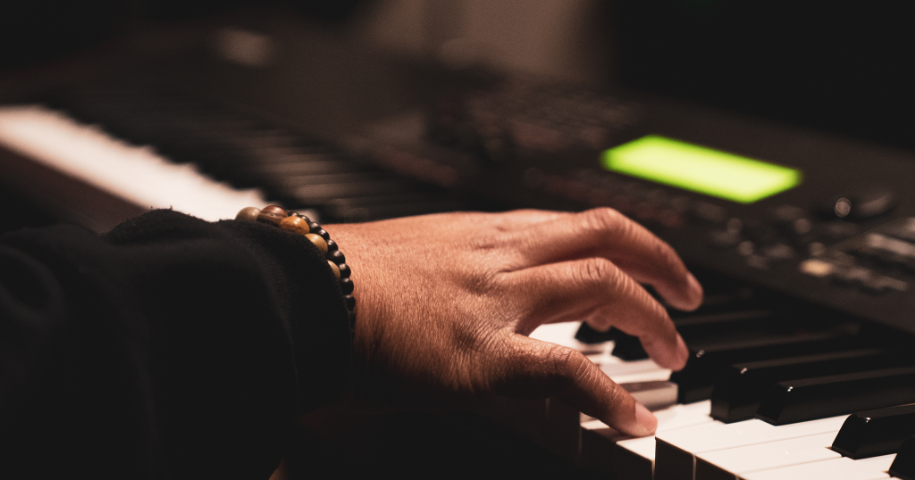 A right hand playing several notes on a digital piano keyboard