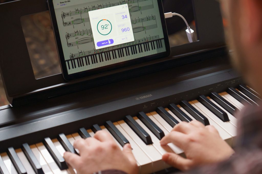 Hands on a keyboard of someone learning piano using the Playground Session app, which is displaying a 92% accuracy score