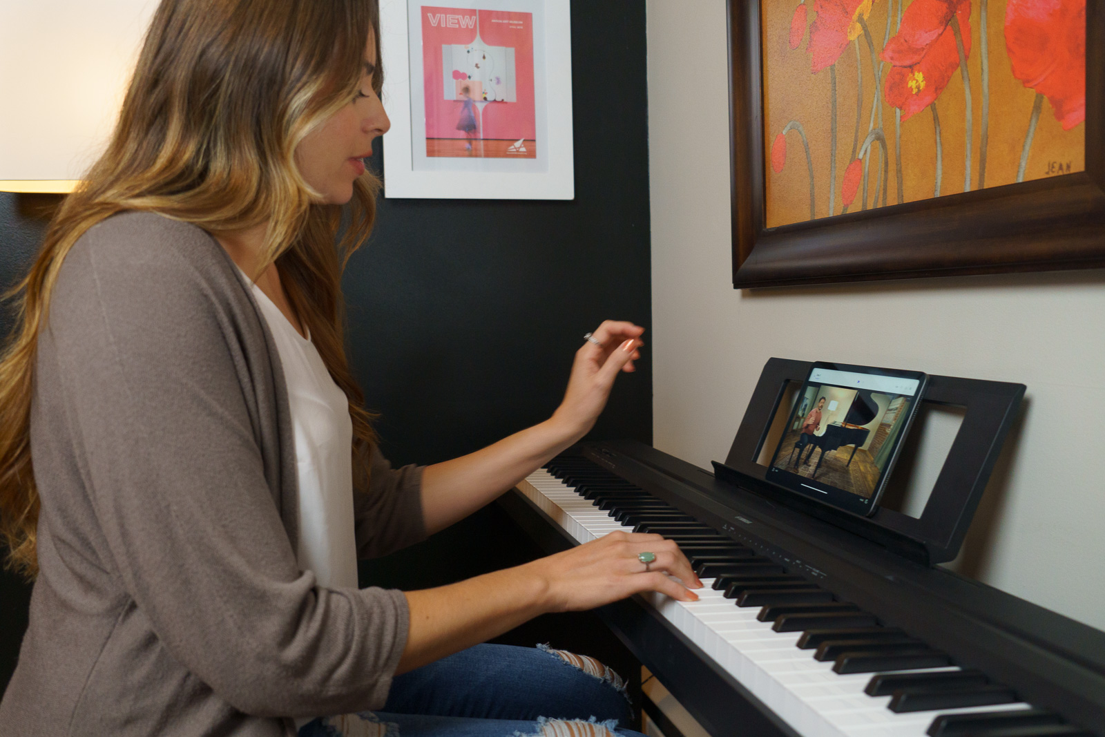 A woman plays a digital piano keyboard while watching a video lesson in the Playground Sessions piano learning app