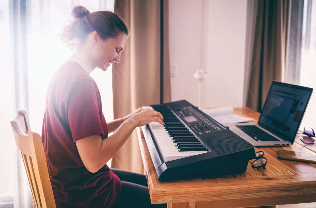 A smiling woman playing a digital piano keyboard