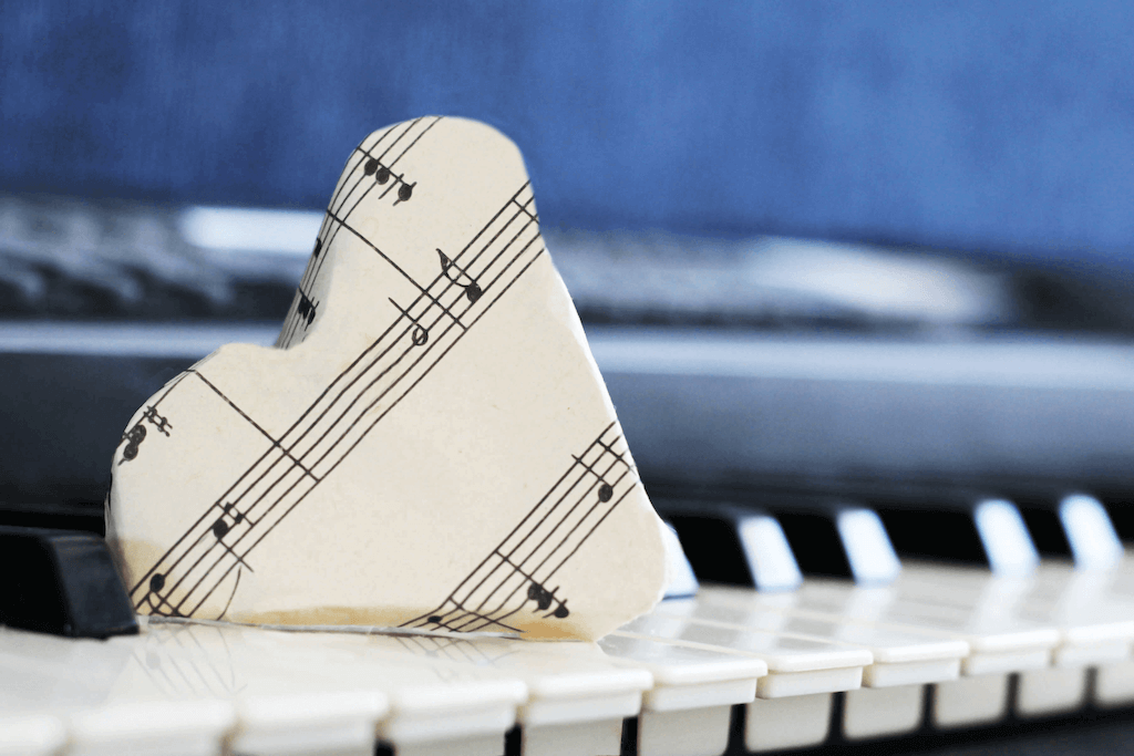 Sheet music wrapped into the shape of a heart on top of piano keys