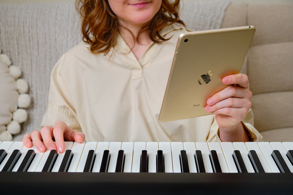 Woman learning how to play piano songs using an ipad 