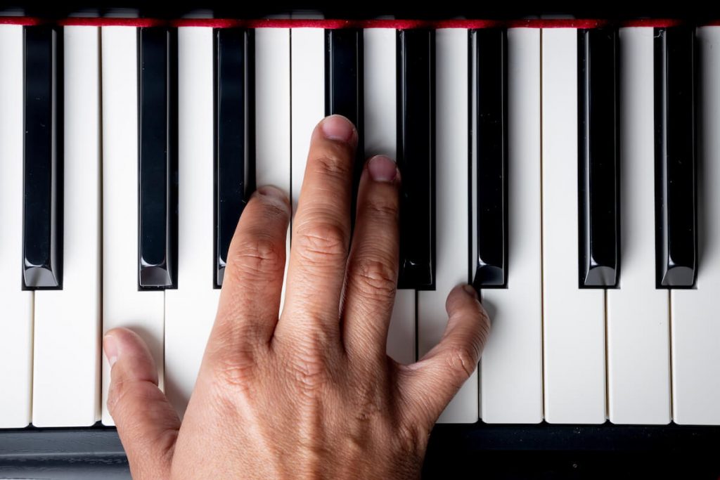 A right hand playing several notes on a piano keyboard
