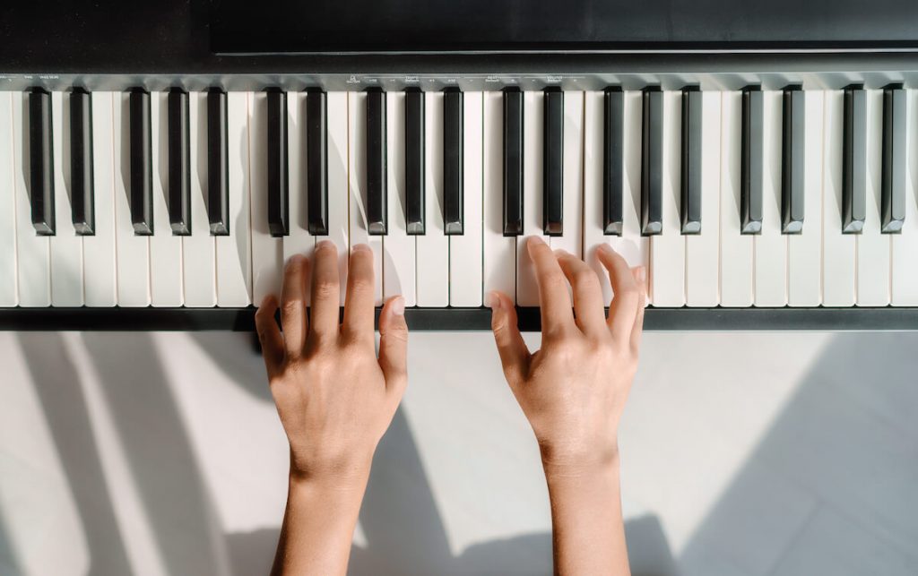 Two hands on a keyboard demonstrating easy piano chords to play